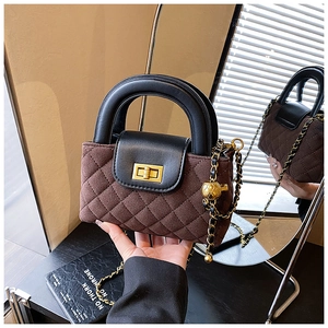 Detailed view of brown quilted bag with gold sphere chain and black leather flap contrast