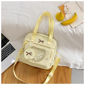Detail of cream canvas ita bag with heart window and brown bow embroidery detail