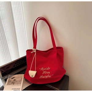 Detail of red canvas tote bag with white embroidery and a small hanging pouch for accessories