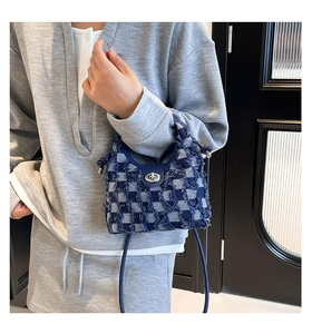 Detail of blue denim bucket bag with checkerboard pattern and silver metal swivel lock