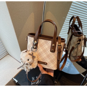 Detail of British plaid handbag with a cute plush rabbit charm and pearl bow accessory