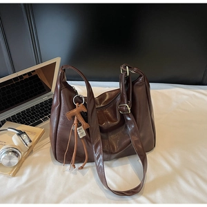 Detalle del bolso tote de cuero PU marrón oscuro con elegante accesorio de borla de moda