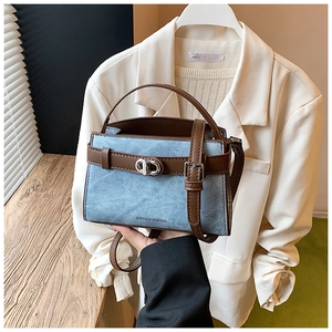 Close-up of denim blue bucket bag with brown leather handles and silver twist lock