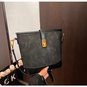Detailed shot of black patchwork bucket bag with golden buckle and textured leather surfaces