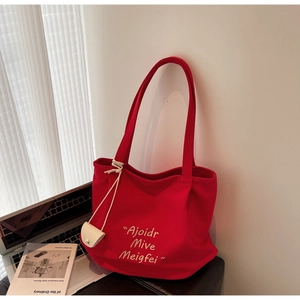 Detail of red canvas tote bag with yellow letter embroidery and mini white pouch