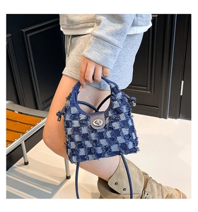 Detail of checkered denim bucket bag featuring frayed edges and silver metal twist lock