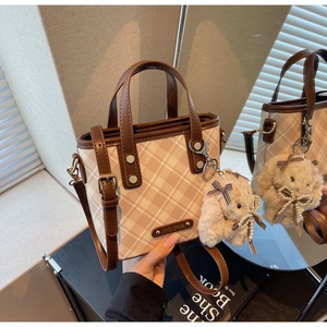 Detail of a vintage plaid crossbody bucket bag with a cute plush bunny keychain