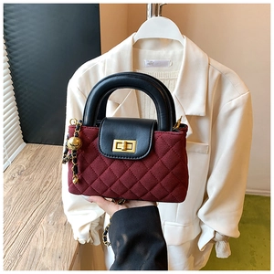 Detailed close-up of wine red quilted handbag with golden twist lock and chain strap