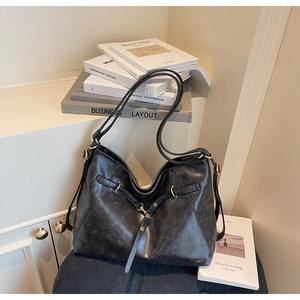 Detail of the black vintage tote bag with aged leather texture and metallic buckle accents