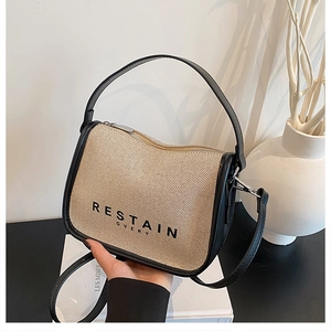Close-up of beige canvas crossbody bag with black leather trim and silver metal zipper
