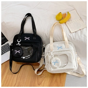 Detail of canvas tote bag featuring heart-shaped clear window and bow-embroidered coin purse