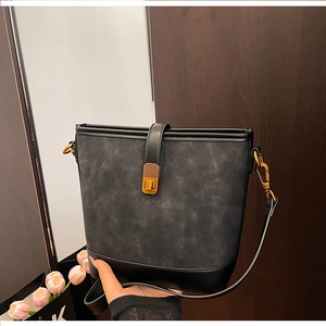 Detail of vintage black bucket bag featuring textured leather and gold clasp closure