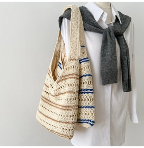 Detailed shot of hand-woven hollow tote bag with blue and brown stripes on model