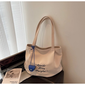 Detail of canvas tote bag with contrast blue pouch, placed near a laptop for scale