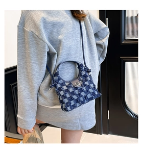 Detail of frayed edges and blue checkered denim texture on stylish bucket bag