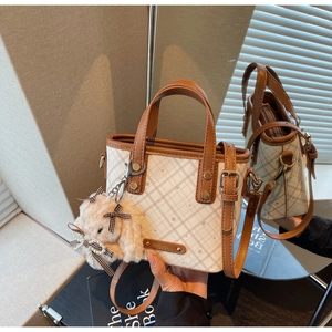 Detail of white plaid tote bag with brown leather trim and cute plush bunny charm