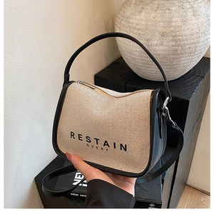 Detail of canvas crossbody bag with woven texture, leather handles and contrast logo