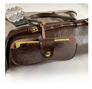 Close-up of deep brown oil wax leather Boston bag showing golden metal buckle and side pocket