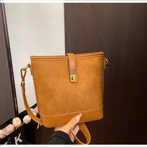 Close-up of caramel bucket bag with matte texture and gold metallic clasp detail