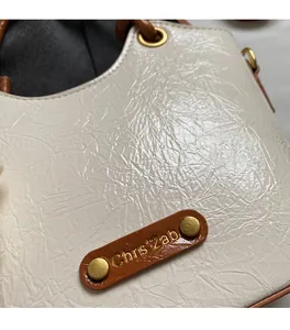 Detail of cream pleated texture fabric with brown leather accent and gold metal rivets