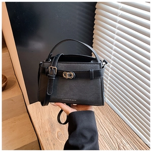 Detailed close-up of a black textured leather bucket bag with silver twist lock and top handle