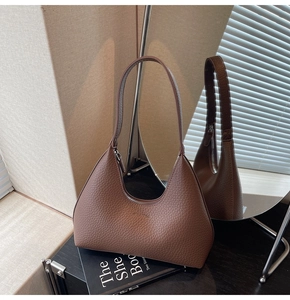 Detail showing brown pebble leather texture and KILARFOU logo on a hobo bag