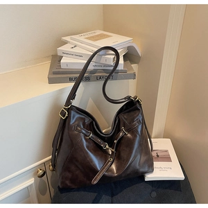 Detail of dark brown faux leather tote with adjustable straps and metal buckles