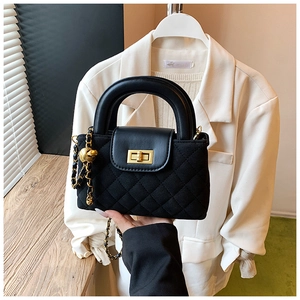 Detailed view of black quilted crossbody bag featuring golden ball chain and twist lock