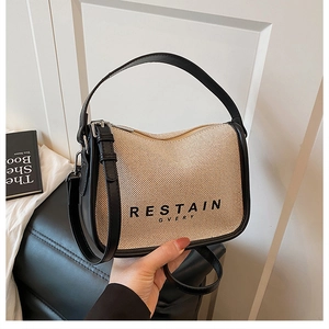 Detail of canvas tote bag with woven texture, leather trim, and adjustable crossbody strap