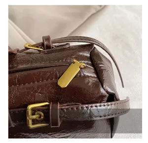 Macro view of dark brown leather bag with glossy gold zipper and textured surface