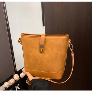 Detail of caramel bucket bag featuring suede textures, smooth leather trim and gold twist lock
