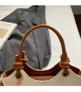 Close-up of bucket bag showing textured pebble finish, brown handle, and metal hardware
