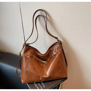 Detail of vintage brown leather tote bag texture and metal buckle on a desk