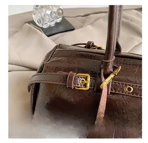 Close-up of retro dark brown leather bag with vintage gold metal hardware and buckle details