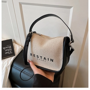 Detail of beige canvas tote with black leather trim and RESTAIN EVERY lettering