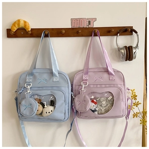 Detail of canvas ita bag featuring a large clear PVC window and bow embroidery