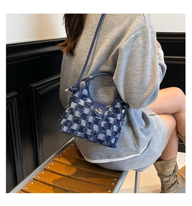 Detail view of denim plaid bucket bag with frayed edges and silver metallic turn-lock closure