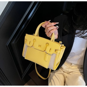Detail of yellow pebbled leather and canvas bucket bag with stitching and hardware