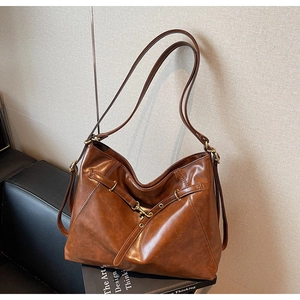 Detail of vintage brown tote bag with decorative metal buckle and soft leather texture
