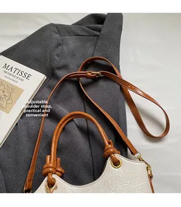 Detail of cream pleated leather bucket bag with adjustable brown strap and gold hardware