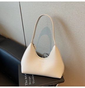 Detail of hobo bag showing off-white pebbled leather texture on design books