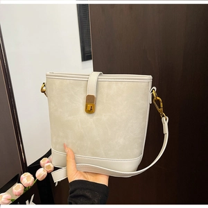 Close-up of a light grey suede bucket bag with gold twist lock and tulip detail
