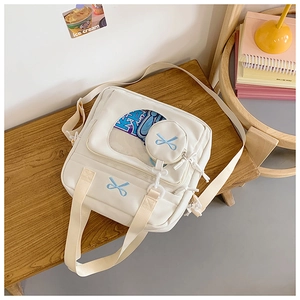 Detail of white canvas crossbody ita bag with clear PVC window and blue bow embroidery