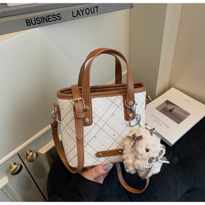 Detail of color-block mini bag with checkered pattern and plush rabbit charm accessory