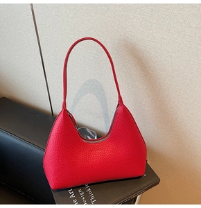 Detail view of red pebbled leather hobo bag with silver zipper on a studio prop