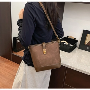 Detail view of dark brown bucket bag showing suede stitching and gold metal buckle closure