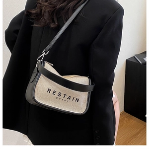 Detail view of canvas crossbody bag with leather trim and artistic text on black blazer