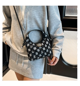 Close-up of black and white plaid bucket bag with fringe trim and silver metal buckle
