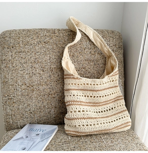 Detail of hand-woven straw tote bag with brown stripes on a soft textile surface