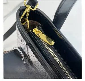 Detail of smooth gold zipper and lobster clasp on check pattern bucket bag